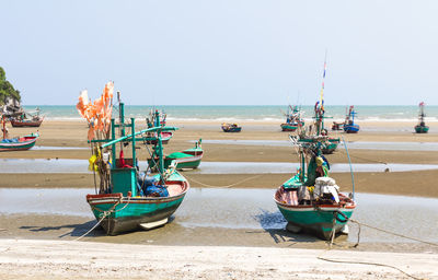 Boats moored on beach against clear sky