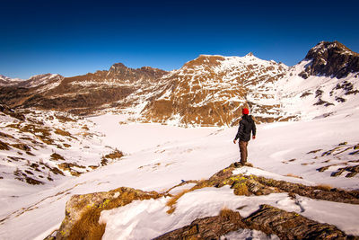 Man standing on snowcapped mountain against sky