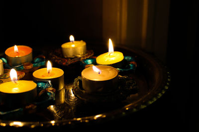 Close-up of illuminated tea light candles dish on table