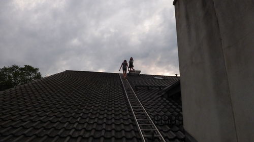 Low angle view of people on roof against sky