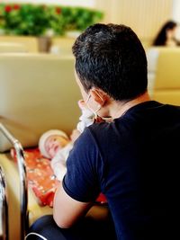 Side view of young woman sitting on chair at home