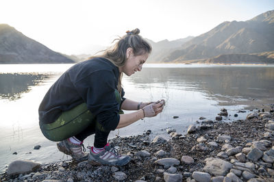 Woman putting mud on hands and face while enjoying outdoors in nature.