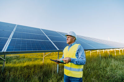 Engineer with tablet pc standing against solar plant