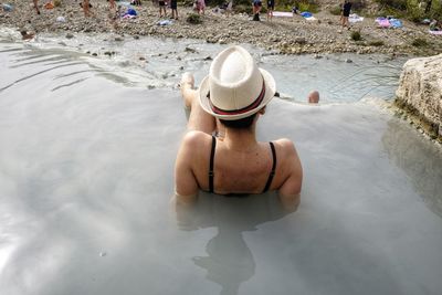 Rear view of woman sitting in water