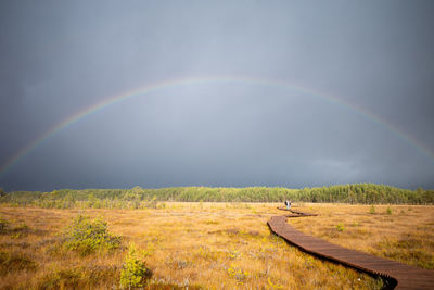 Scenic view of field against rainbow in sky