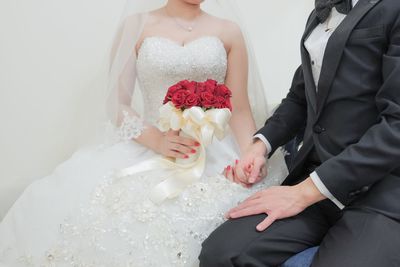 Midsection of couple holding bouquet
