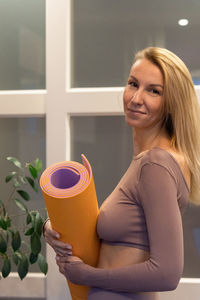 Portrait of beautiful young woman holding colorful mat for sports. sport and healthy lifestyles
