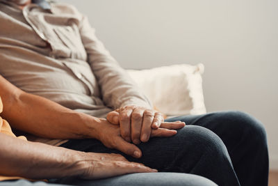 Midsection of man sitting on sofa at home