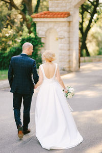 Rear view of couple walking with umbrella