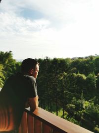 Man standing by railing against sky