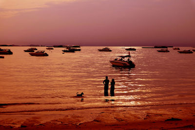 Silhouette people on beach against sky during sunset