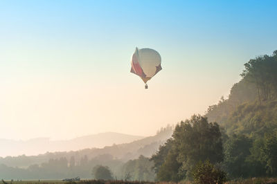 Hot air balloon flying over trees against sky