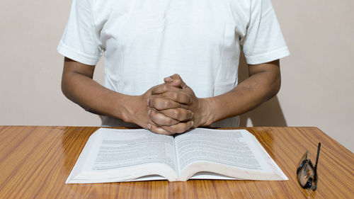 Midsection of man reading book on table