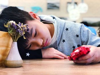 Close-up of boy with toy while relaxing at table