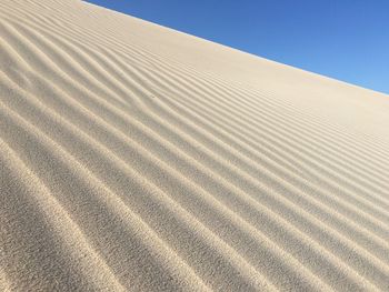 Sand dunes in desert against clear blue sky