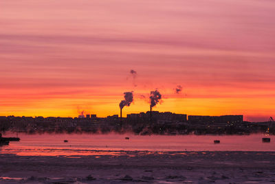 Smoke emitting from factory against sky during sunset