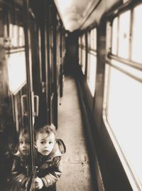 High angle portrait of curious boy standing in train corridor by window