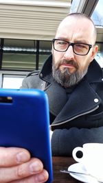 Close-up of man using mobile phone while sitting on table