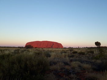 Scenic view of land against clear sky during sunset