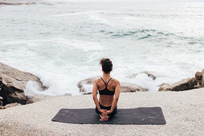 Rear view of woman sitting at beach