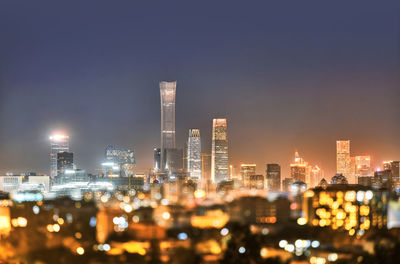 Illuminated buildings in city against sky at night