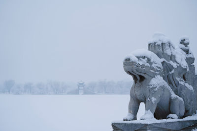 Statue of snow covered landscape against sky