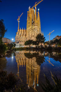 The famous sagrada familia in barcelona at night reflected in a small pond