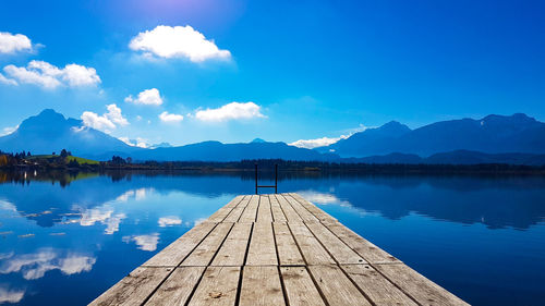 Wooden pier on calm lake against mountain range