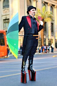 Man with colorful umbrella in costume performing on city street during carnival