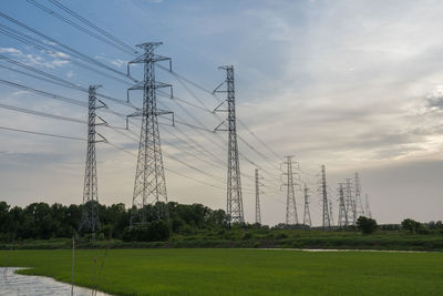 Low angle view of electricity pylon on field against sky