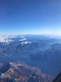 Aerial view of snowcapped mountains against blue sky