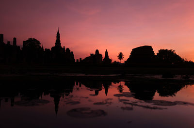 Reflection of silhouette buildings in water at sunset