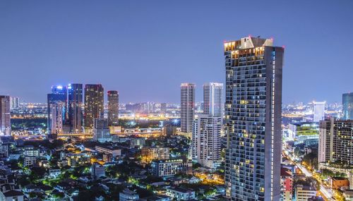 Illuminated buildings in city against clear sky