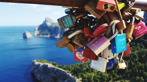 Padlocks hanging on railing against sea