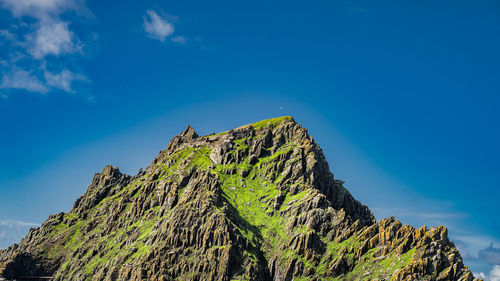 Low angle view of rocks against blue sky