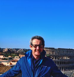 Portrait of mature man standing against blue sky