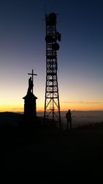 Silhouette man standing by statue against sky