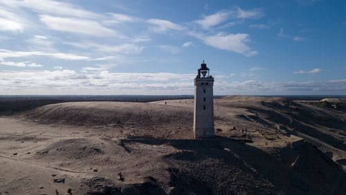 Lighthouse amidst buildings against sky