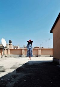 Rear view of woman standing against clear blue sky