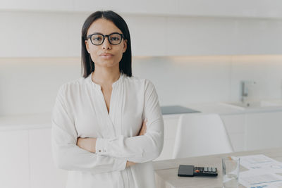 Portrait of young woman standing against wall