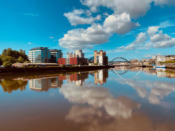 Reflection of buildings in river against sky