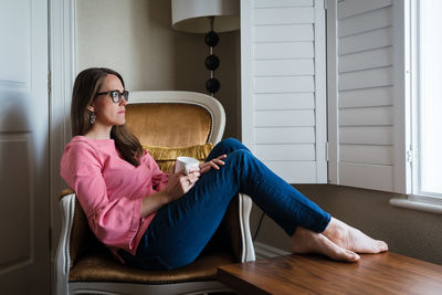 Young woman using mobile phone while sitting on floor at home