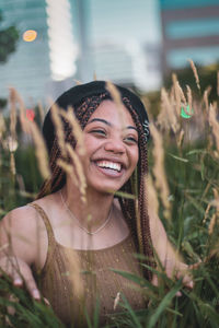 Close-up of cheerful young woman looking away amidst plants