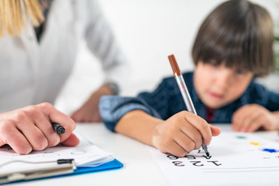 Teacher and student drawing on table in classroom