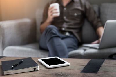 Midsection of woman using mobile phone while sitting on sofa