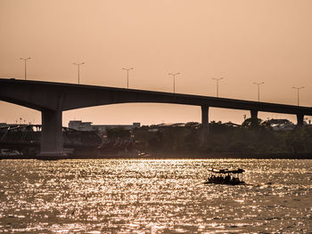 Silhouette bridge over river against sky during sunset