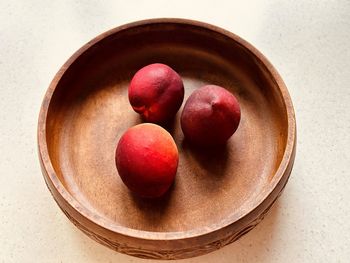 Three nectarines in wooden bowl.overhead. fresh, colourful, juicy, sweet, nutritious, summer fruit.