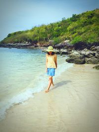 Full length of woman walking at beach against clear sky