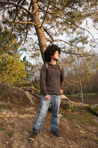 Full length of teenage girl standing by tree in forest