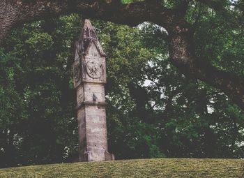 Low angle view of clock tower amidst trees and building